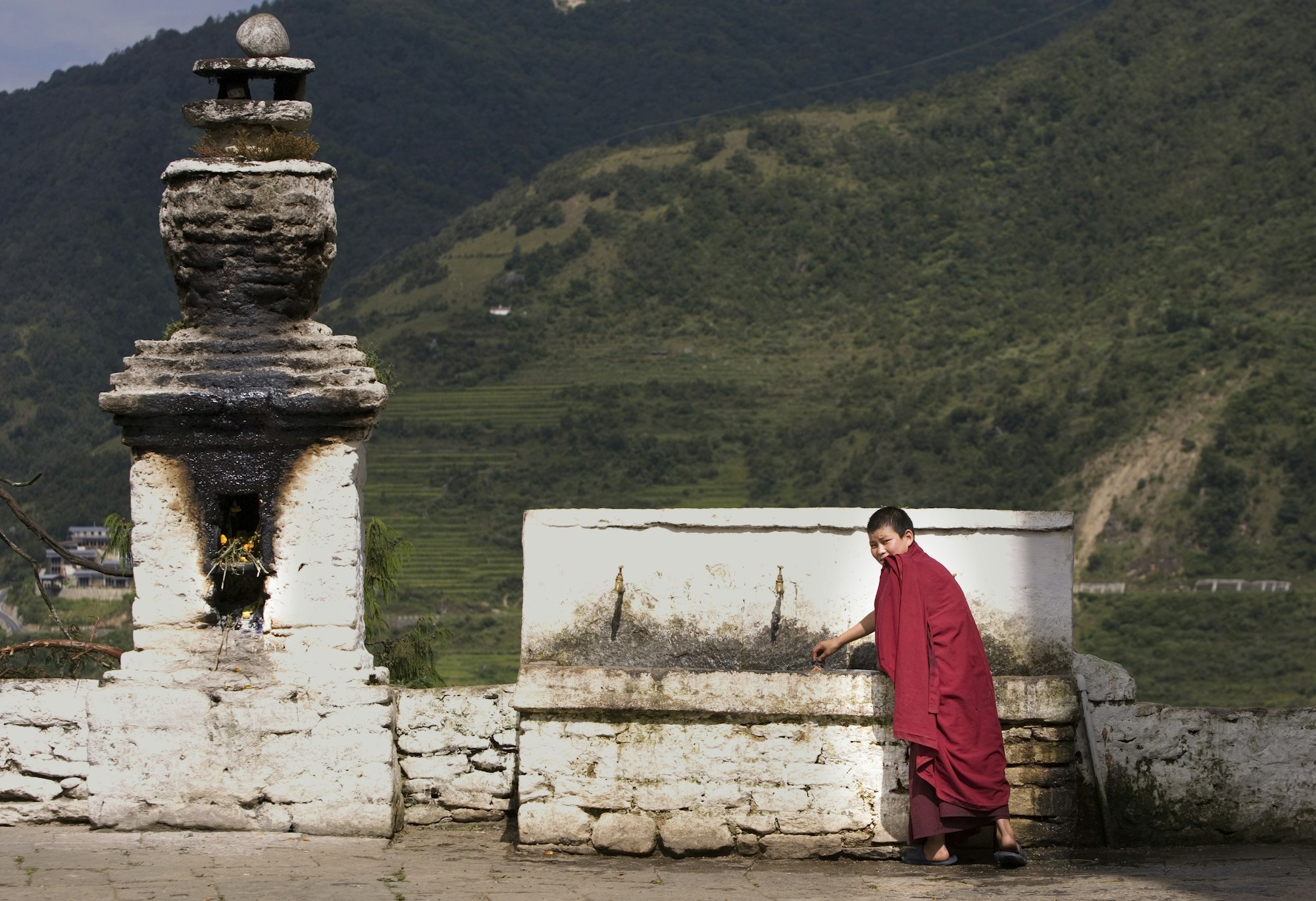 Portrait of young buddhist monk drinking at temple fountain, Punakha, Bhutan